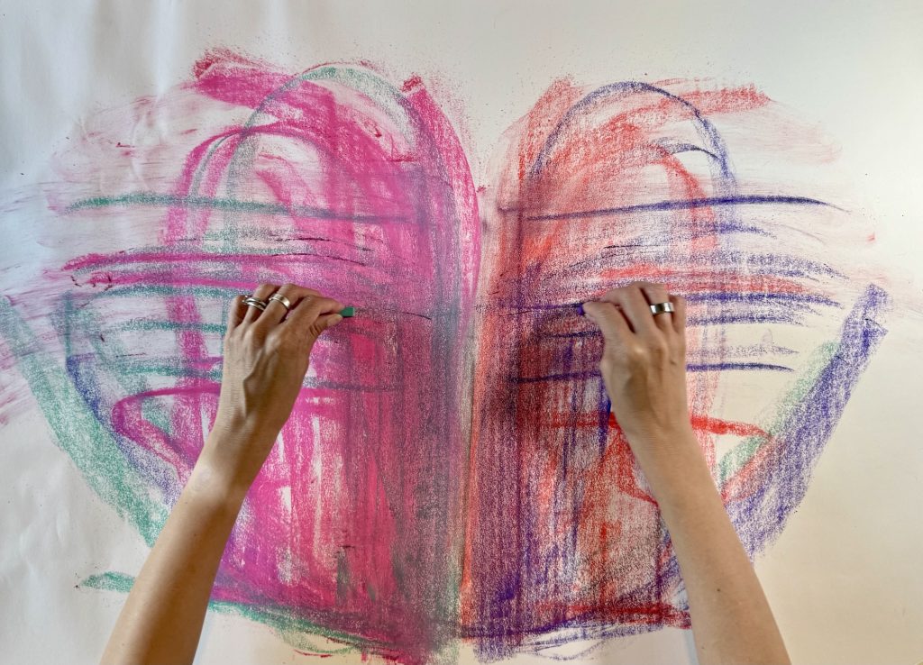 Oil pastel bi-lateral drawing with two hands using pinks, orange, blues and purple.